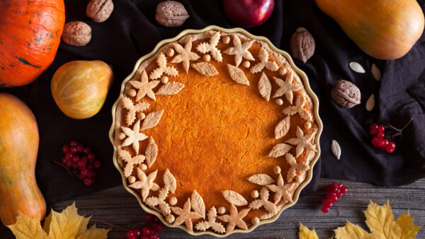 A freshly baked Thanksgiving pumpkin pie with a smooth orange filling and flaky crust on a kitchen table.
