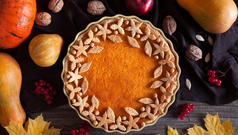A freshly baked Thanksgiving pumpkin pie with a smooth orange filling and flaky crust on a kitchen table.