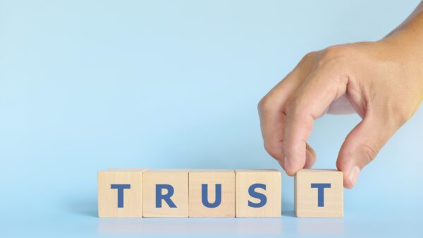 Build trust concept. Hand stacking wooden blocks with word trust.