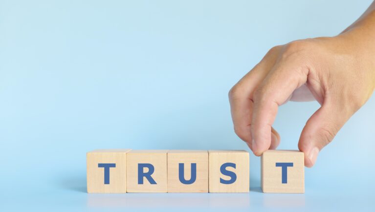 Build trust concept. Hand stacking wooden blocks with word trust.