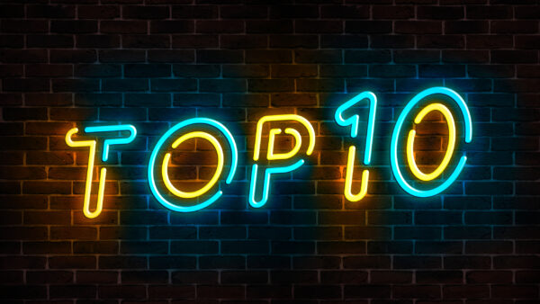 Top 10 neon blue and yellow light text on empty red brick wall banner. Bright sign of top ten list winners at night. Design template of modern signboard or advertising