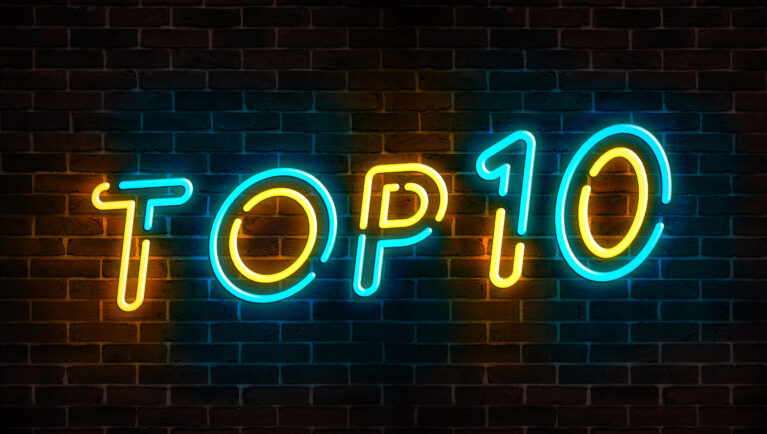 Top 10 neon blue and yellow light text on empty red brick wall banner. Bright sign of top ten list winners at night. Design template of modern signboard or advertising