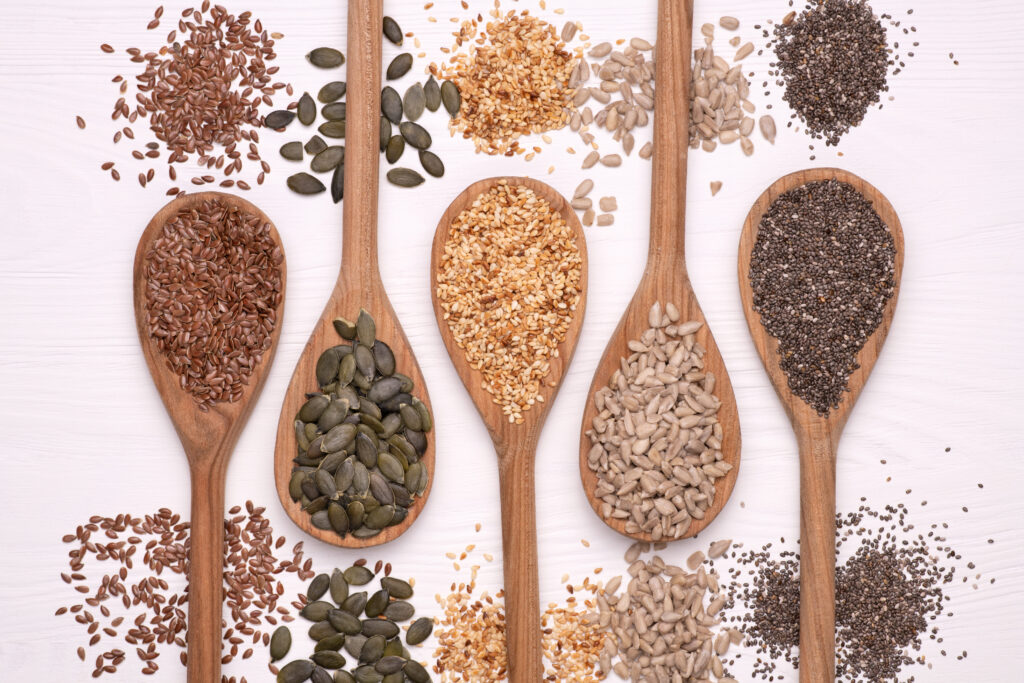 Healthy seeds - sesame, flax seed, sunflower seeds, pumpkin seed, chia in wooden spoons on a white background. Top view