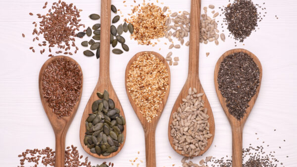 Healthy seeds - sesame, flax seed, sunflower seeds, pumpkin seed, chia in wooden spoons on a white background. Top view