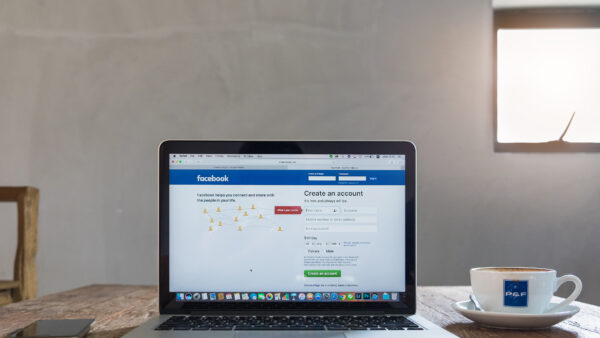 Laptop computer on wooden desk and Browsing Facebook Website, login screen. facebook is a photo-sharing. facebook is a social network.