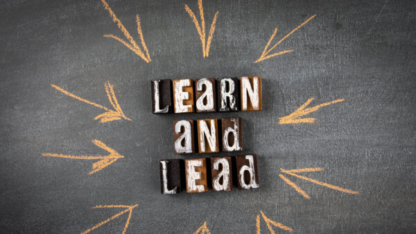 Learn and Lead. Letters of the alphabet with text on a dark chalk board