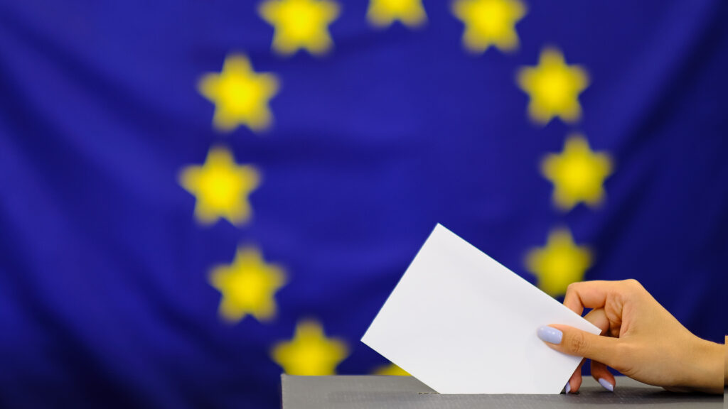 Hand holding ballot paper for election vote concept. elections, The hand of woman putting her vote in the ballot box. on european union flag background