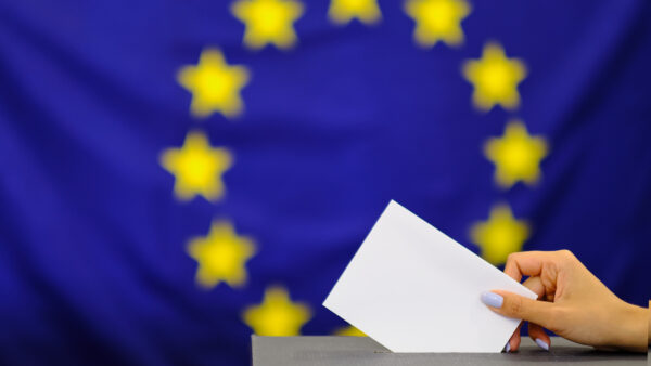 Hand holding ballot paper for election vote concept. elections, The hand of woman putting her vote in the ballot box. on european union flag background